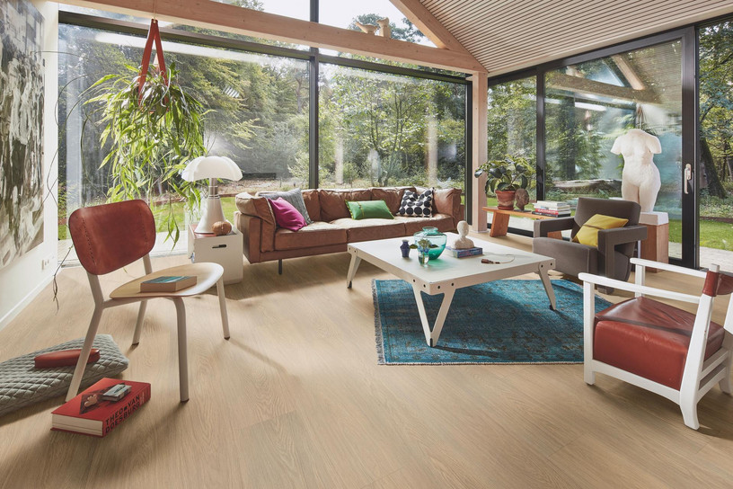 Helles Wohnzimmer mit Vinylboden ohne PVC in Eiche-Optik und großer Glasfront.