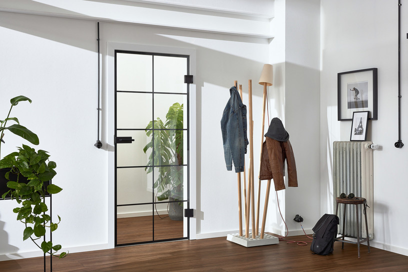 Loft-Glastür mit schwarzem Gitterrahmen in heller Garderobe.