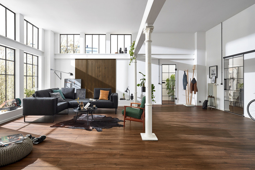 Großer Wohnraum mit Lofttür aus Glas und dunklem Designboden.